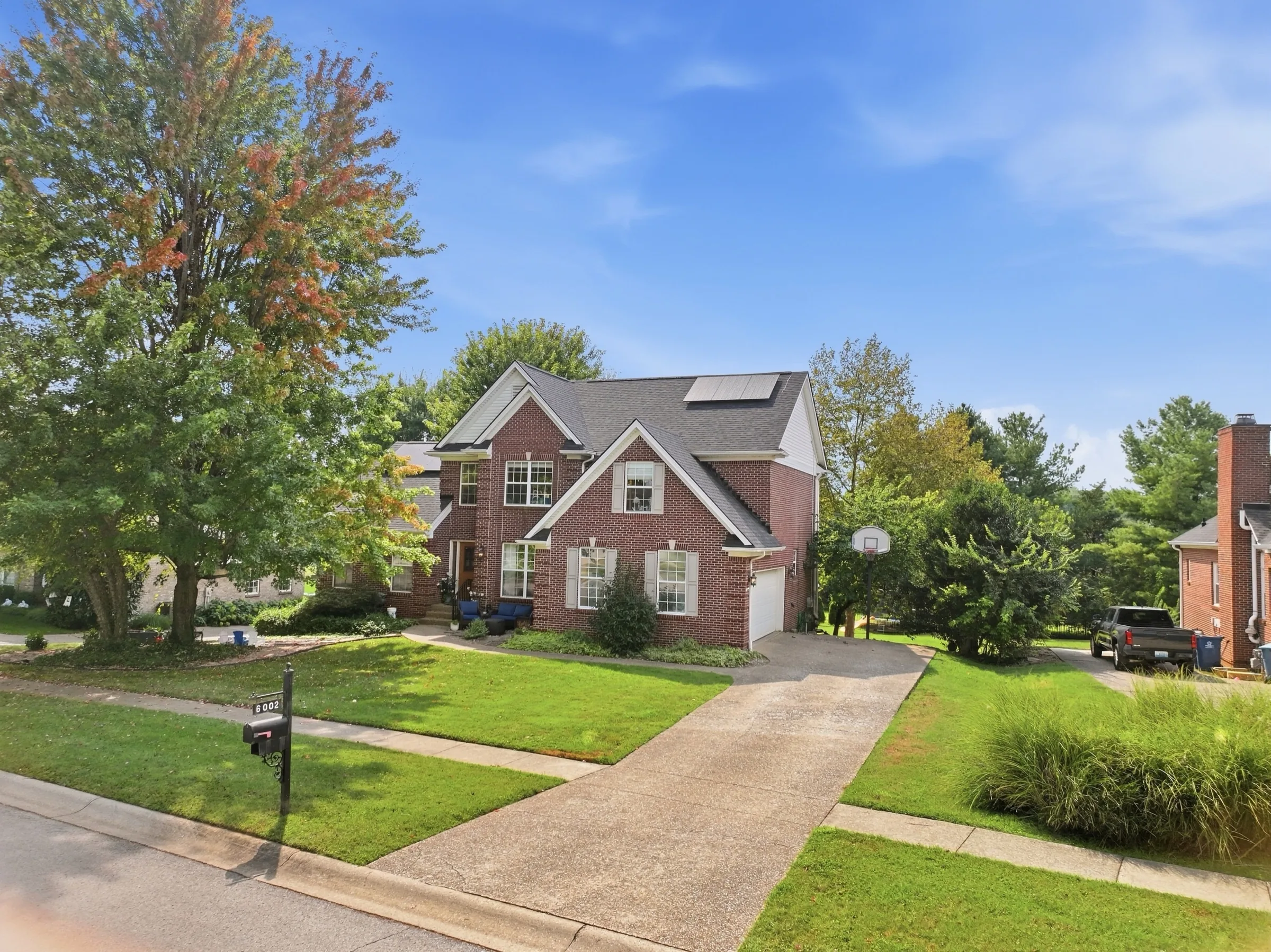 The front of 6002 John Moser Way: a two-story brick house behind a green lawn