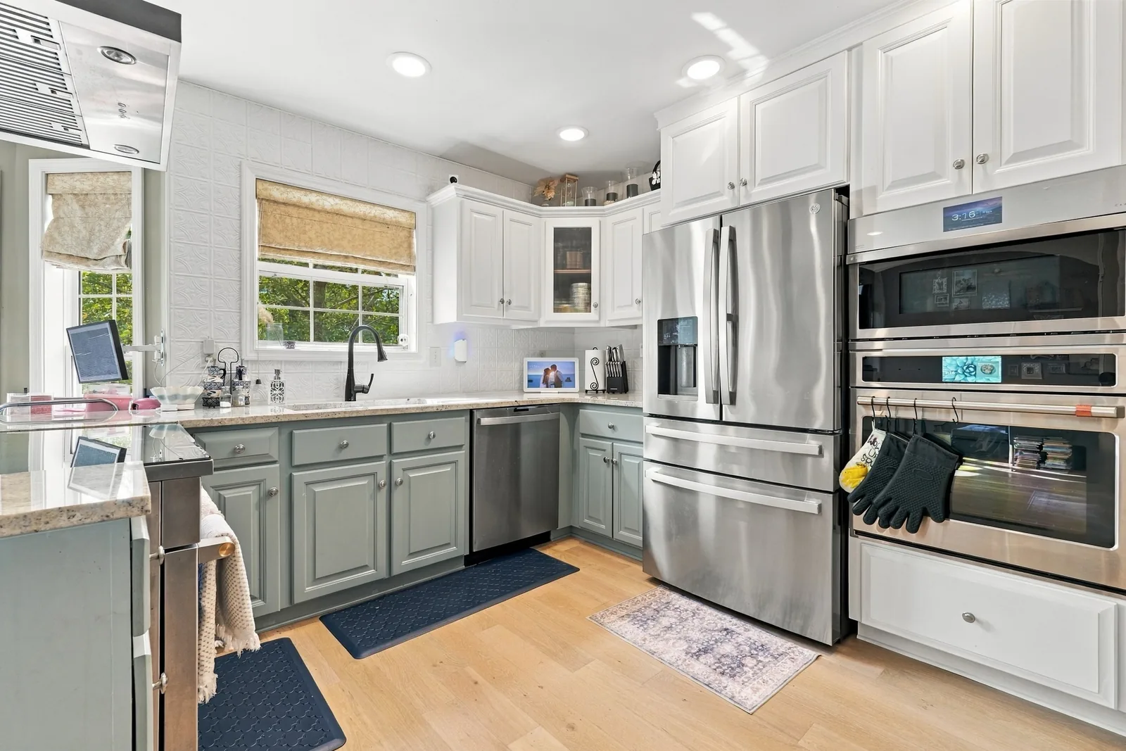 Kitchen with white upper and sage lower cabinets and stainless appliances
