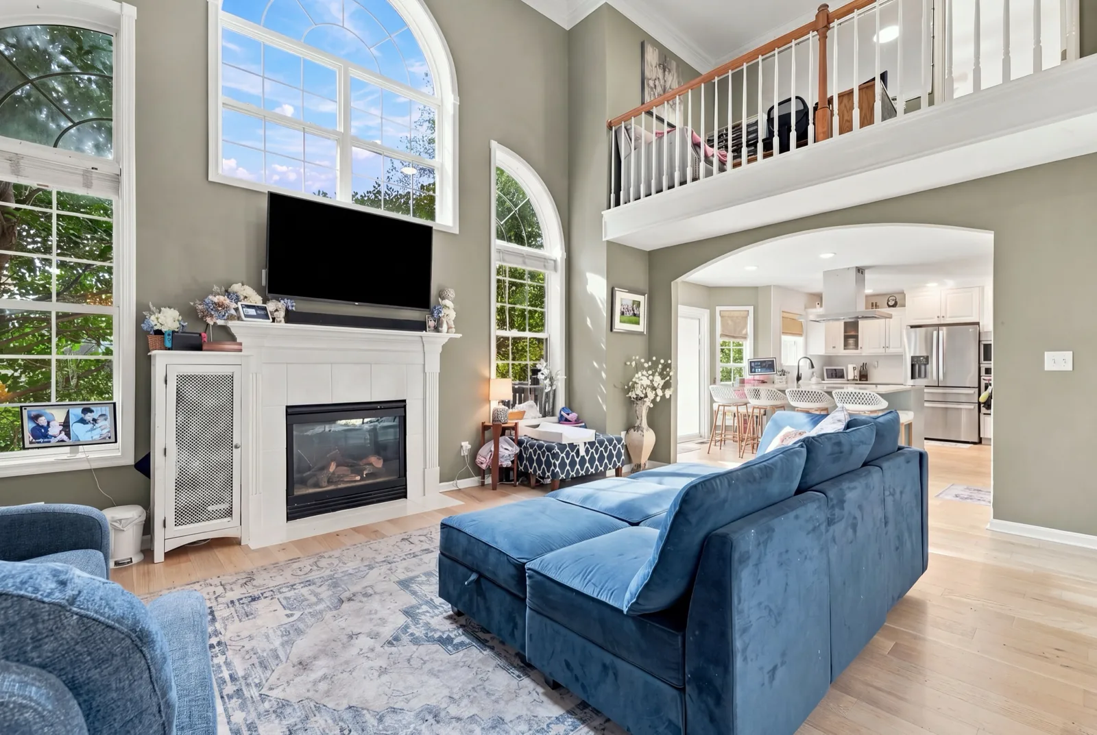 The two-story living room with arched windows, a fireplace and the upstairs landing