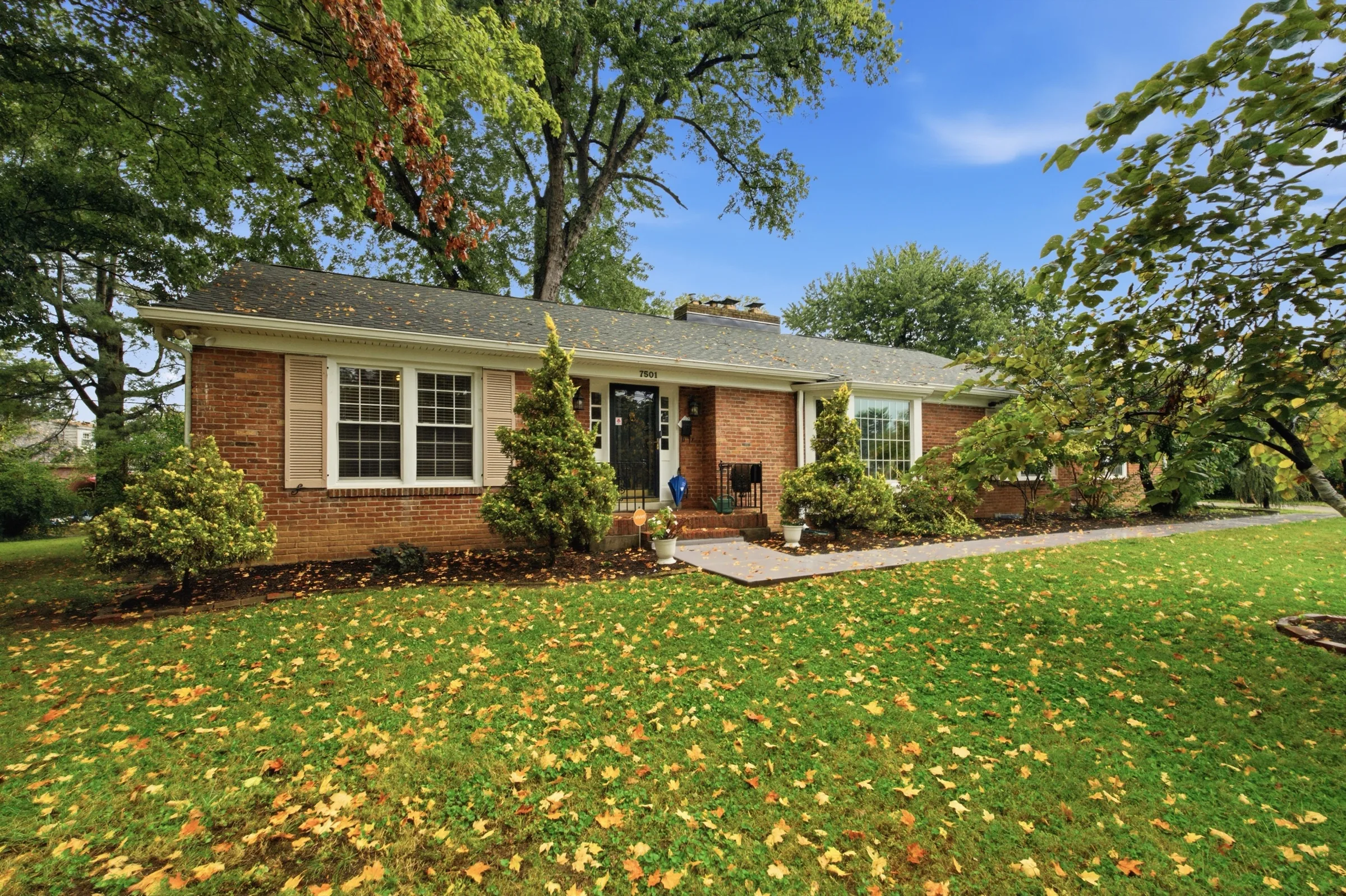 The front of 7501 Tudor Ct: a brick ranch behind a lawn under mature trees